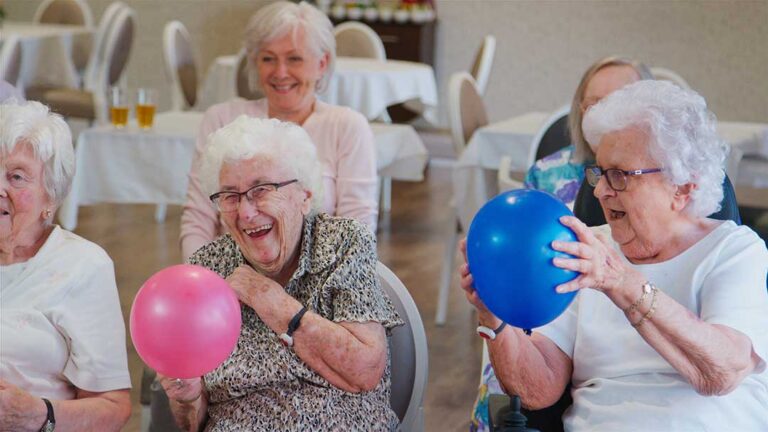 Family members review a resident’s care documents with an assisted living staff member at a table.
